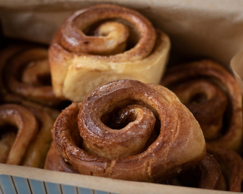 Close-up of freshly baked cinnamon rolls in a box, perfect for baking enthusiasts.
