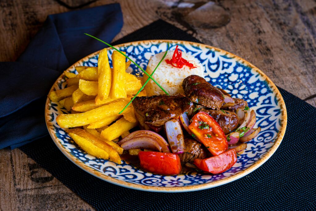 Authentic Lomo Saltado dish with fries and rice, served on a decorative plate.