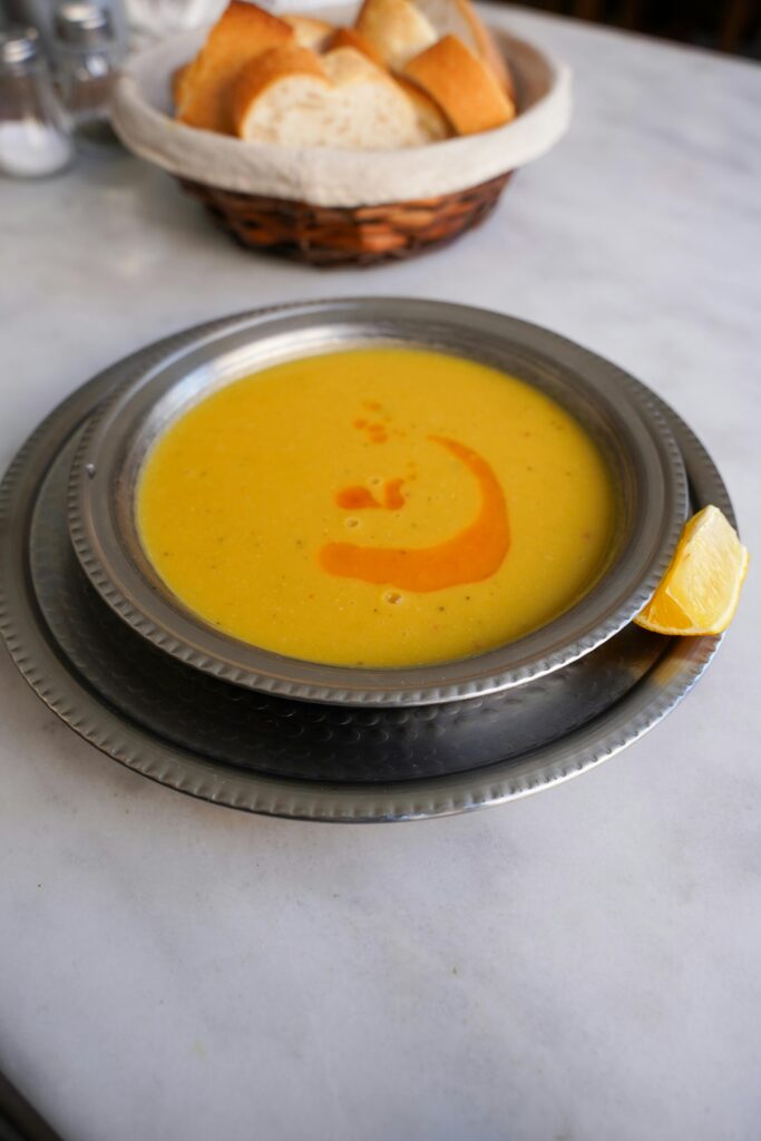 A bowl of traditional Turkish soup with bread and lemon slice on marble table in Bursa, Türkiye.