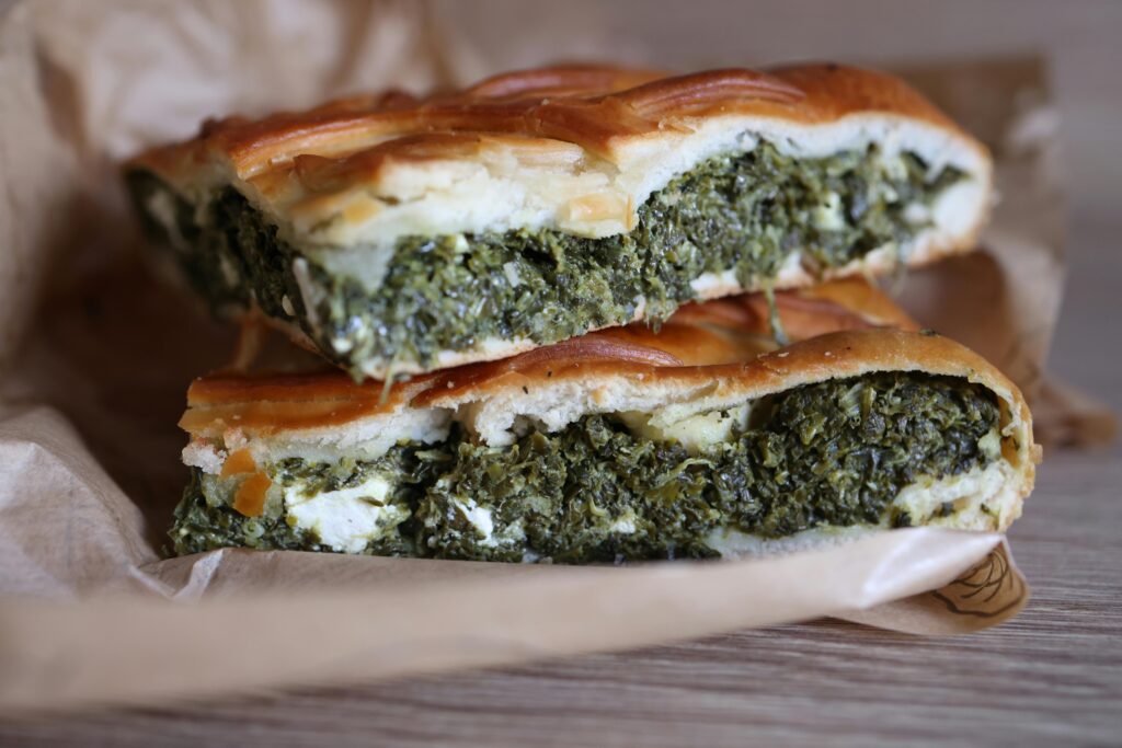 Close-up of fresh spinach and feta spanakopita slices on parchment paper.