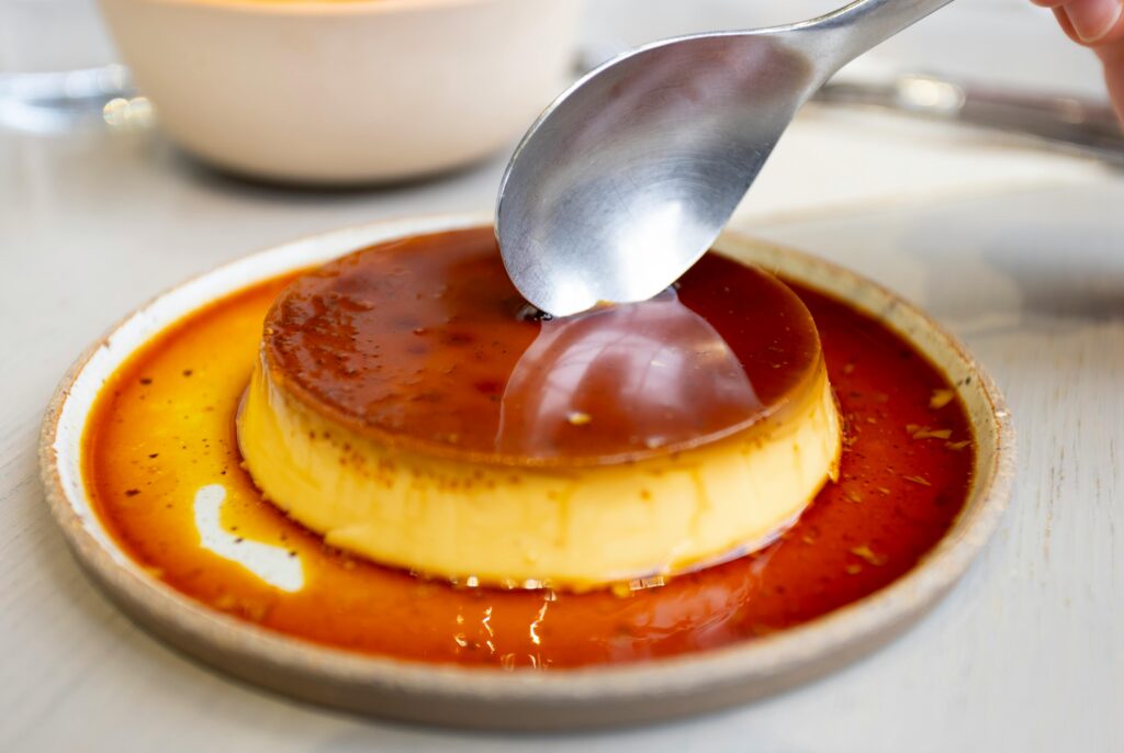 Close-up of a caramel flan dessert being served in a cozy café setting in Tokyo.